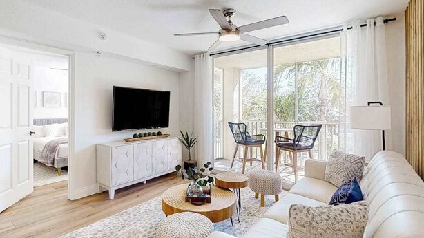 Een moderne woonkamer met een bank, salontafel en stoelen, een televisie en een balkon met uitzicht.