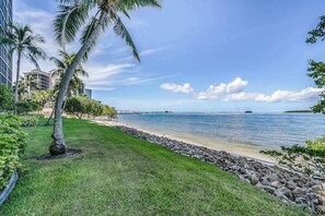A coastal view with a grassy area, palm trees, and a clear sky. - Bayfront escape with beach access, and panoramic coastal views (Fort Myers)