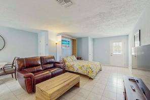 A bedroom with a bed, a brown leather sofa, a wooden coffee table, and a desk with a computer. - Coastal Manasota Key Quadruplex, Dog-Friendly Studio, Snowbird Specials (Unit C) (Englewood)