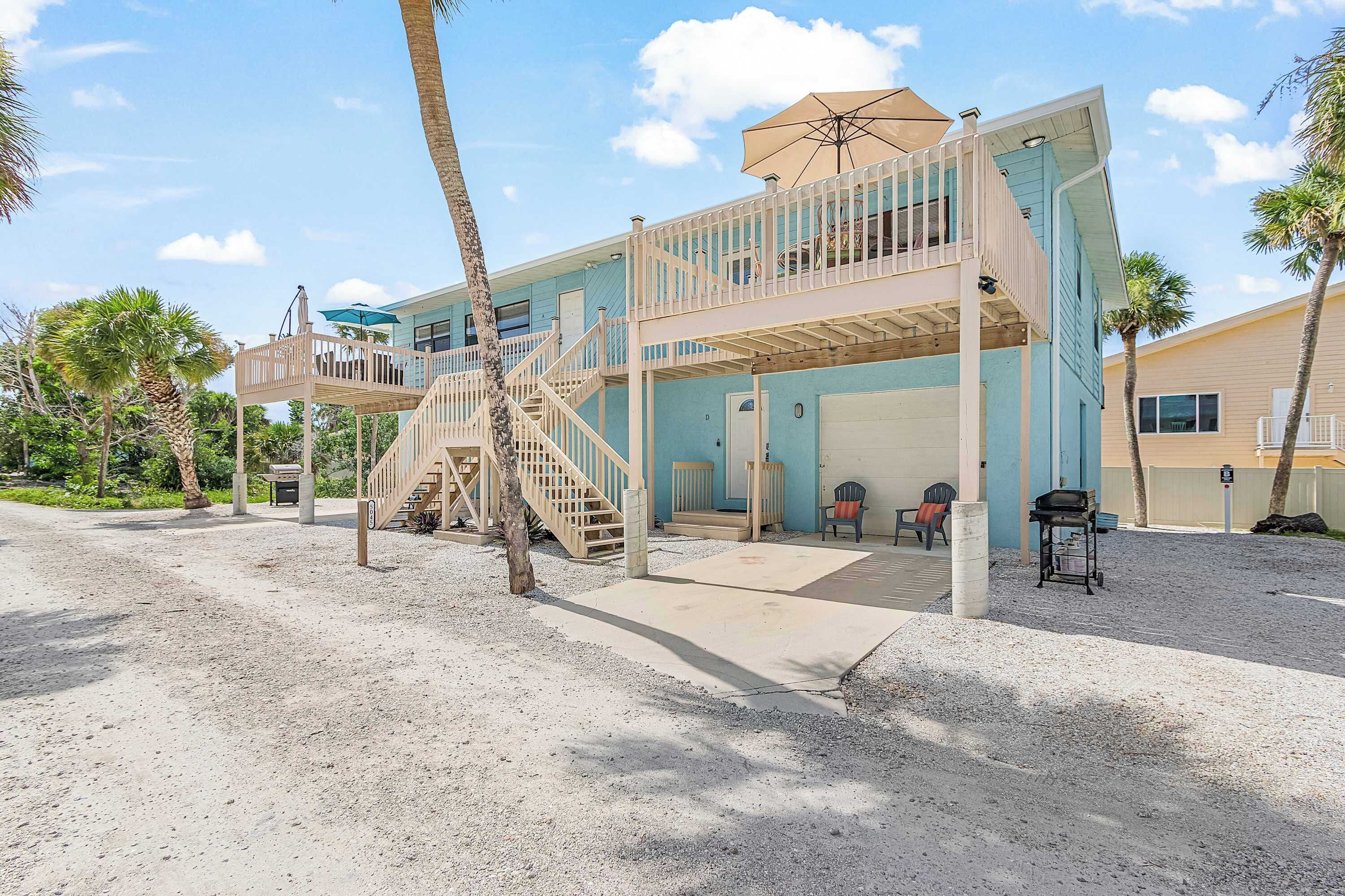 A two-story building with a balcony, a staircase, and a covered outdoor seating area.