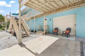 A two-story building with a covered patio area, a staircase, and a garage door. - Coastal Manasota Key Quadruplex, Dog-Friendly Studio, Snowbird Specials (Unit C) (Englewood)