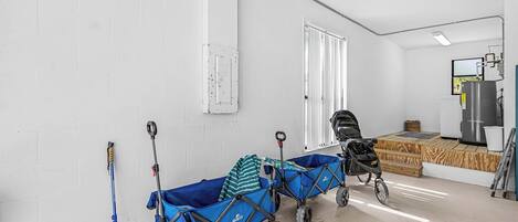 A room with a blue utility cart, a stroller, and a water dispenser.