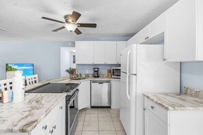 A modern kitchen with white cabinets, a built-in oven, a dishwasher, and a refrigerator.