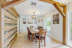 A dining area with a wooden table and chairs, a ceiling fan, and artwork on the walls. - Coastal home with private pool, arcade games, and firepit (Fort Myers)