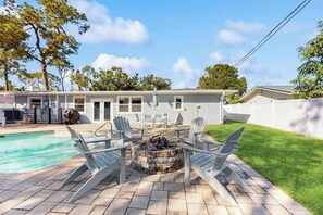 A backyard with a swimming pool, a fire pit, and outdoor furniture. - Coastal home with private pool, arcade games, and firepit (Fort Myers)