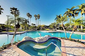 A swimming pool with palm trees, a rock feature, and a tiled deck. - Chic Gulf Villa | Pools, Hot Tub, Sports Courts, Fishing Pier | Mins to Beach (Fort Myers)