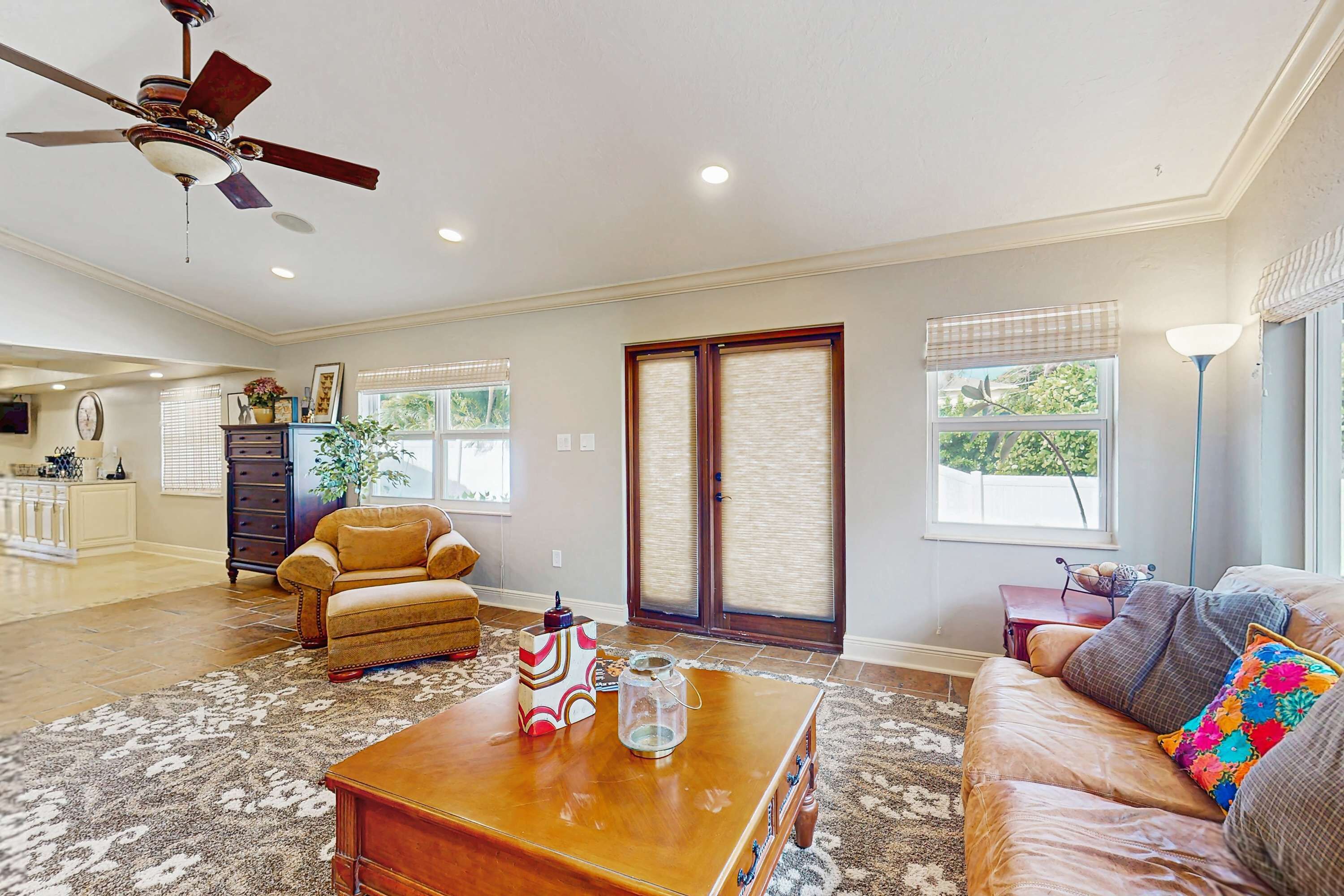 A spacious living room with a wooden coffee table, leather sofa, and a ceiling fan.
