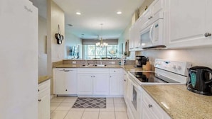 A modern kitchen with white cabinets, a built-in oven, a microwave, and a coffee maker. - Upgraded Greenlinks Golf Villas Condo | All-New Appliances | Luxe Pool & Spa (Naples)