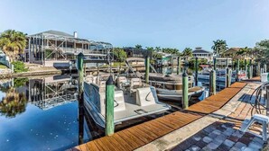 Un port de plaisance avec des bateaux amarrés, une structure couverte et une passerelle en bois.
