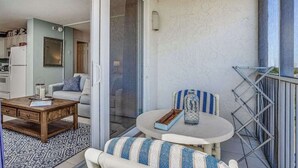 Un balcon avec une table à manger, un canapé et une chaise.