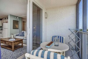 Ein Balkon mit Esstisch, einer Couch und einem Sessel.