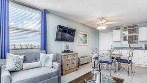Un salon comprenant un canapé, un téléviseur et un coin repas avec des chaises.