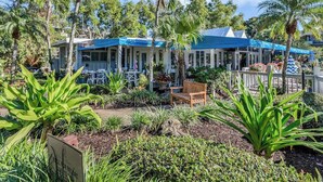 Un restaurant doté d’une terrasse, entouré de plantes tropicales et de palmiers.