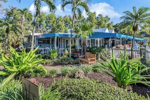 A restaurant with outdoor seating, surrounded by tropical plants and palm trees. - Ideal Naples Getaway W/ Shared Pool, Tennis Courts, & Central AC (Naples)