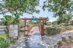 A wooden bridge leading to a gated area with a sign listing amenities like a restaurant, pool, spa, gazebo, and tennis court. - Ideal Naples Getaway W/ Shared Pool, Tennis Courts, & Central AC (Naples)