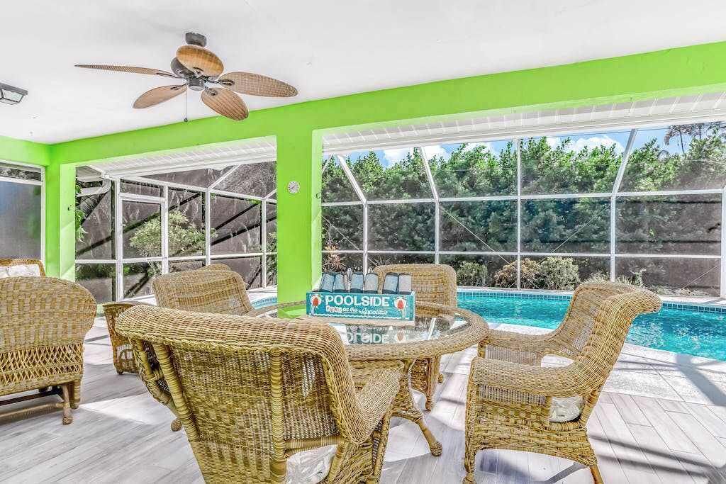 A poolside area with wicker furniture, a ceiling fan, and a sign for 'POOLSIDE.'