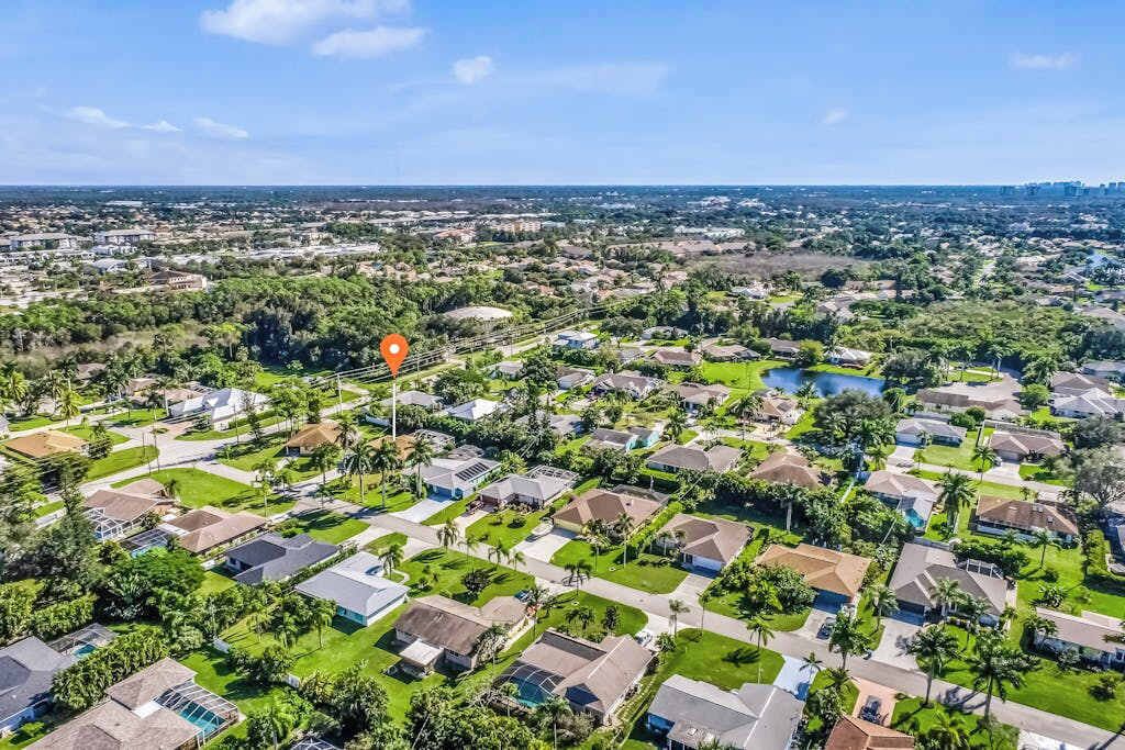 A residential area with houses, green lawns, and a clear sky.