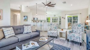 A modern living room with a sofa, armchairs, a coffee table, and a ceiling fan. - Beautiful home with private pool & lanai - near beaches & parks (Bonita Springs)