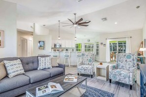 Un salon moderne avec un canapé, des fauteuils, une table basse et un ventilateur de plafond.