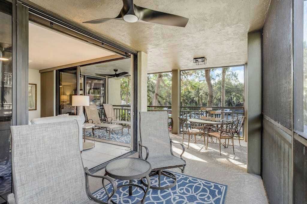 A balcony with seating, a ceiling fan, and a view of the outdoors.