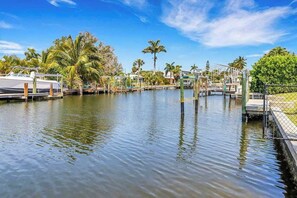 A marina with boats docked, palm trees, and a clear sky. - Serene & sunlit waterfront home with dock, patio, & incredible views - near golf (Bonita Springs)