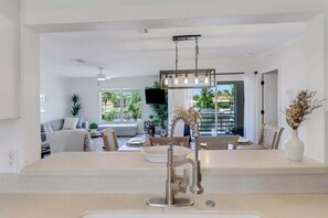 A modern kitchen with a central island, pendant lighting, and a view of the outdoors. - Serene & sunlit waterfront home with dock, patio, & incredible views - near golf (Bonita Springs)