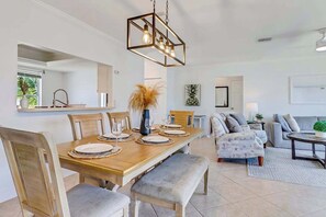 A dining area with a wooden table, chairs, and a hanging light fixture. - Serene & sunlit waterfront home with dock, patio, & incredible views - near golf (Bonita Springs)