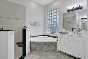 Une salle de bain moderne avec une baignoire sur pieds, une grande fenêtre et un meuble-lavabo avec un miroir.