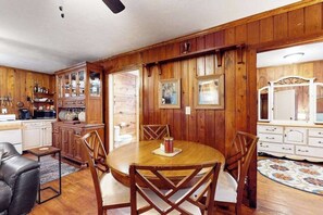A dining area with a wooden table and chairs, a kitchen with wooden cabinets, and a patterned rug. - Classic dog-friendly cottage with kitchen, washer/dryer, & central AC (Bonita Springs)