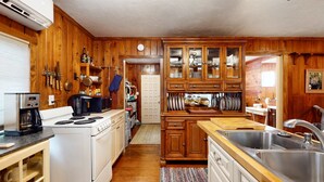 Une cuisine avec des meubles de rangement en bois, une cuisinière, un évier et une machine à café.