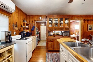 A kitchen with wooden cabinets, a stove, a sink, and a coffee maker. - Classic dog-friendly cottage with kitchen, washer/dryer, & central AC (Bonita Springs)