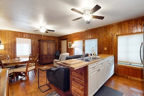 A kitchen with wooden cabinets, a dining area with a table and chairs, a ceiling fan, and a refrigerator. - Classic dog-friendly cottage with kitchen, washer/dryer, & central AC (Bonita Springs)