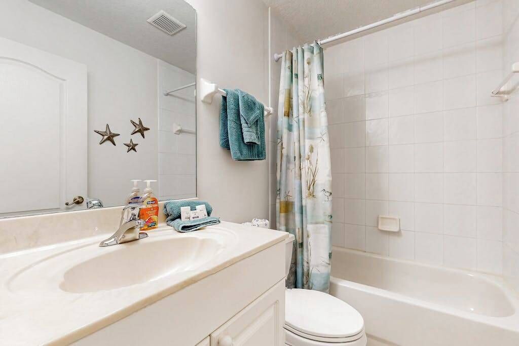 Une salle de bain avec un lavabo blanc, des toilettes et une baignoire.