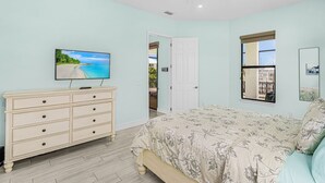 Ein Schlafzimmer mit Bett, Kommode, Fernseher und Deckenventilator.