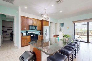 A modern kitchen with wooden cabinets, a central island, and a large window. - Spacious, dog friendly home with pool, on waterway within minutes to the Gulf (Bokeelia)