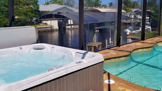 Ein Whirlpool und ein Schwimmbecken mit Blick auf Häuser und ein Gewässer.