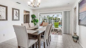 A dining area with a table, chairs, a chandelier, framed artwork, and a view through a glass door. - Canal-front home w/ private pool, hot tub, dock & kayaks/paddleboards -1 dog OK (Cape Coral)