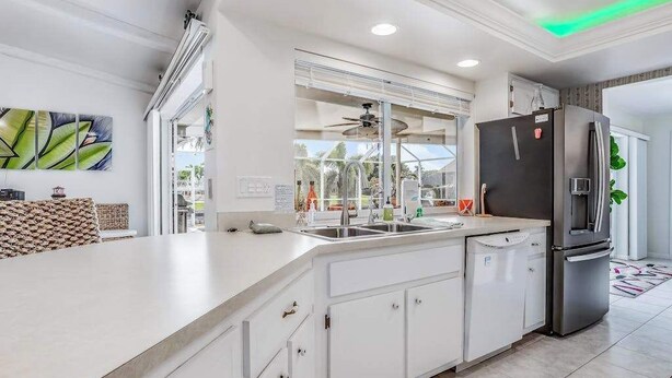 A modern kitchen with white cabinetry, a black refrigerator, a built-in oven, and a window with a view of the outdoors. - Canal-front home w/ private pool, hot tub, dock & kayaks/paddleboards -1 dog OK (Cape Coral)