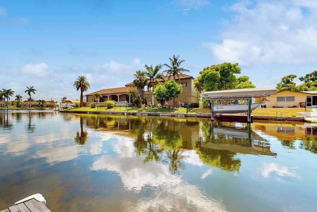 A waterfront property with a dock, a building with a red roof, and palm trees.