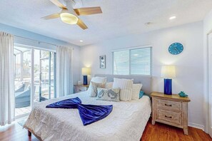 A bedroom with a bed, a ceiling fan, a clock, and a view through the glass door. - Dog-friendly tropical home on the canal w/ screened patio w/ pool & private dock (Cape Coral)