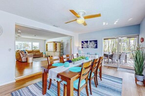 A spacious dining area with a wooden table, chairs, and a ceiling fan. - Dog-friendly tropical home on the canal w/ screened patio w/ pool & private dock (Cape Coral)