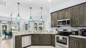 A modern kitchen with dark cabinets, stainless steel appliances, and a large island. - Dog-friendly (hypoallergenic), Heated pool, Game Room, Smart T.V.'s and More (Cape Coral)