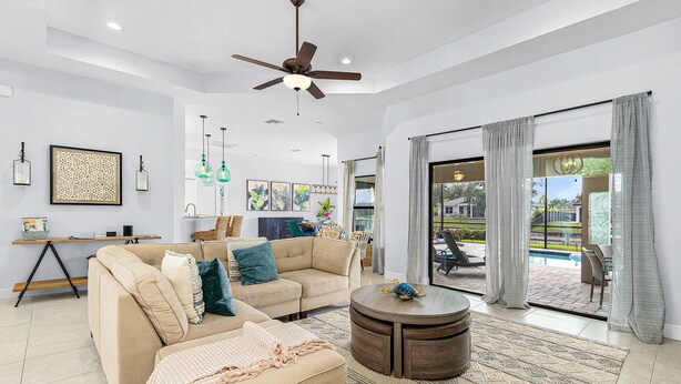 A spacious living room with a sofa, a coffee table, and a ceiling fan. - Dog-friendly (hypoallergenic), Heated pool, Game Room, Smart T.V.'s and More (Cape Coral)