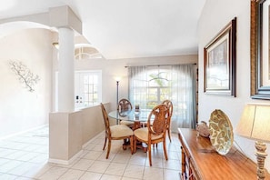 A dining area with a round table, four chairs, a lamp, and a decorative leaf on a wooden table. - Canal-front home with private heated pool, pool spa, dock, kayaks, grill, 1 bike (Cape Coral)