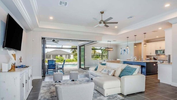 Ein modernes Wohnzimmer mit Sofa, Hocker und Flachbildfernseher.