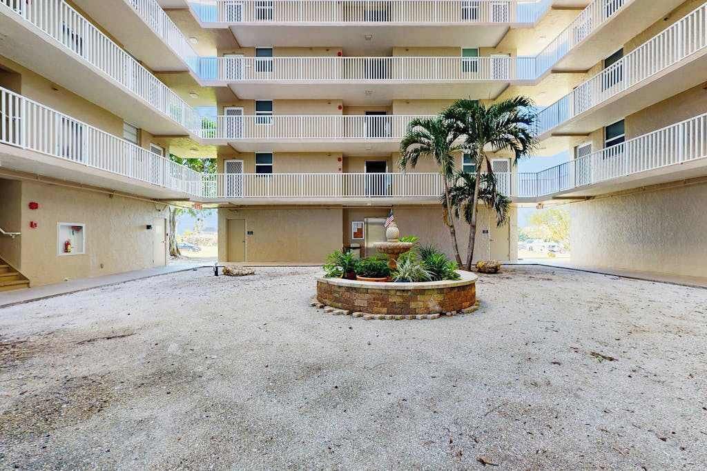 A multi-story building with a central courtyard, balconies, and a palm tree.