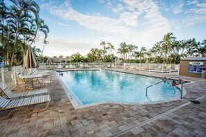 A swimming pool with lounge chairs and palm trees. - Coastal studio with water views, shared pool, and internet (Bonita Springs)