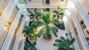Un atrium à plusieurs niveaux, doté d’une cour centrale agrémentée de palmiers et de plantes en pot.