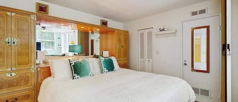 Un dormitorio con una cama grande, un armario de madera y una puerta con la etiqueta 'Sail'.