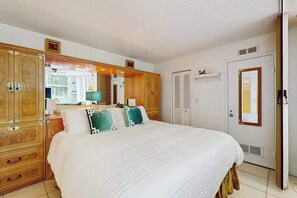 A bedroom with a large bed, wooden wardrobe, and a door labeled 'Sail'. - Coastal studio with water views, shared pool, and internet (Bonita Springs)